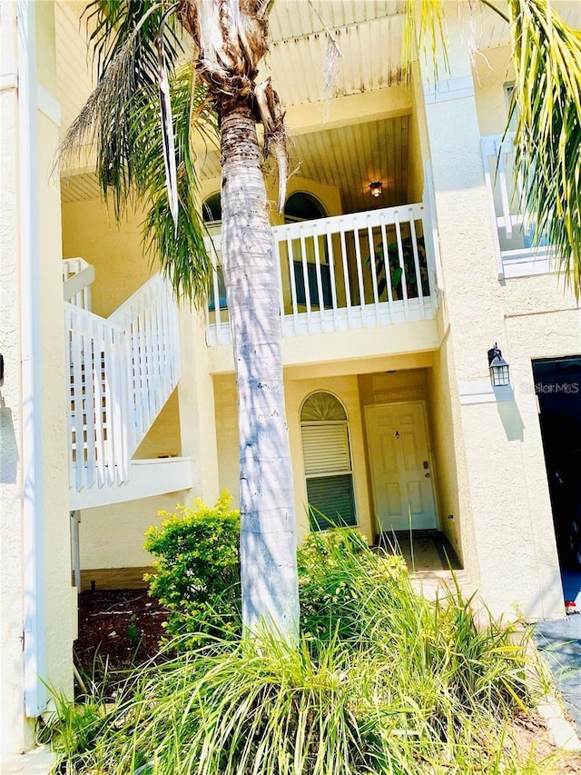 view of exterior entry with stucco siding and a balcony