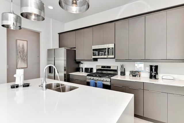 kitchen featuring gray cabinets, a sink, hanging light fixtures, light countertops, and stainless steel appliances