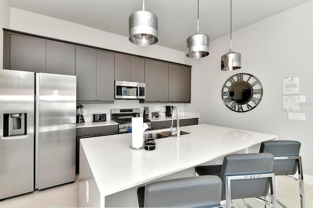 kitchen featuring a sink, a breakfast bar area, light countertops, appliances with stainless steel finishes, and a kitchen island with sink