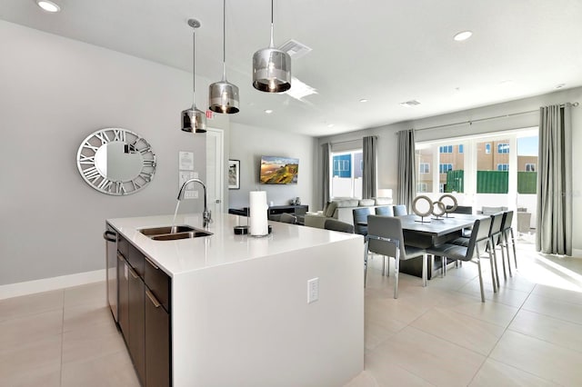 kitchen with dishwasher, light tile patterned flooring, an island with sink, and a sink