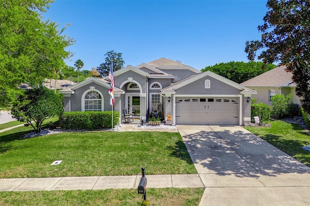 view of front of home with stucco siding, concrete driveway, a front lawn, and a garage