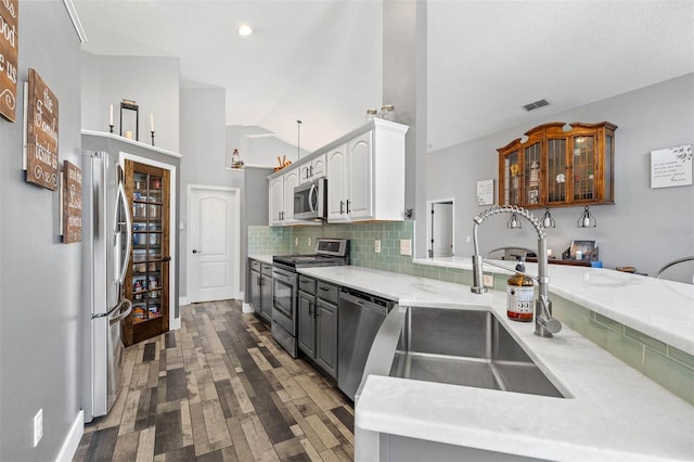 kitchen featuring tasteful backsplash, visible vents, vaulted ceiling, appliances with stainless steel finishes, and a sink