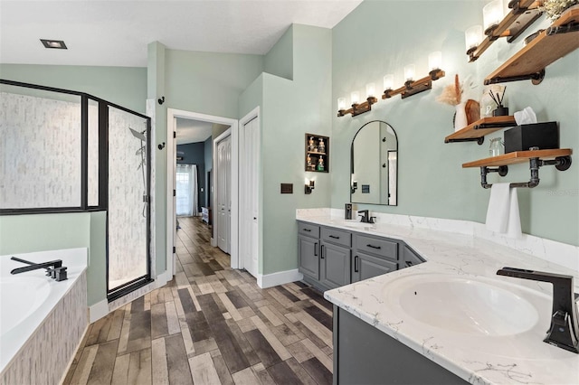 full bathroom featuring a garden tub, vaulted ceiling, a stall shower, wood finished floors, and a sink