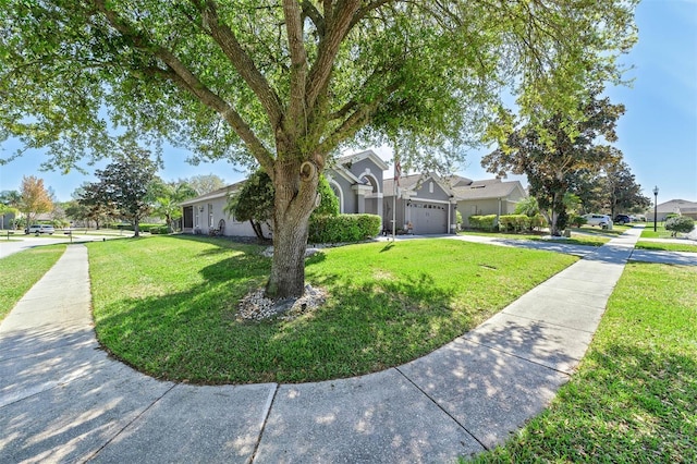 view of front of house featuring a front lawn, an attached garage, a residential view, and driveway