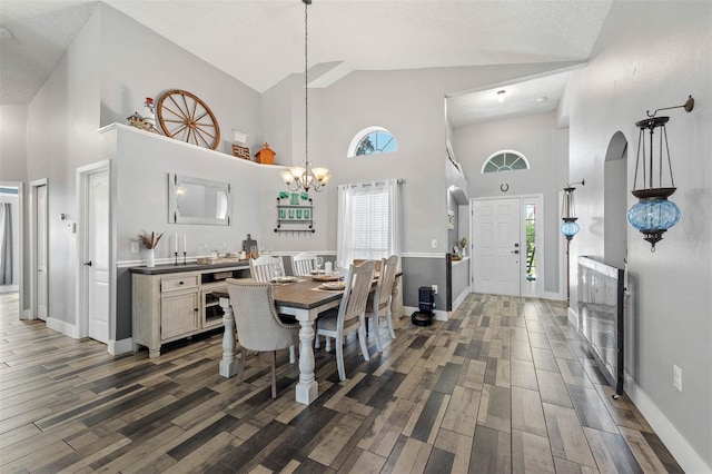 dining space featuring an inviting chandelier, high vaulted ceiling, baseboards, and wood tiled floor