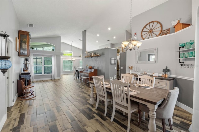 dining space featuring wood finished floors, baseboards, visible vents, high vaulted ceiling, and an inviting chandelier