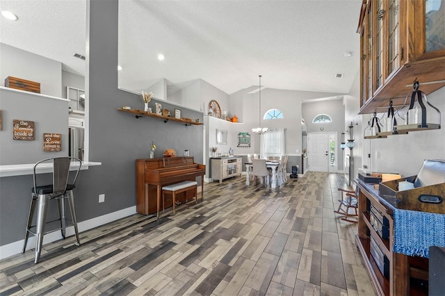 living room featuring visible vents, a textured ceiling, wood finished floors, baseboards, and a chandelier