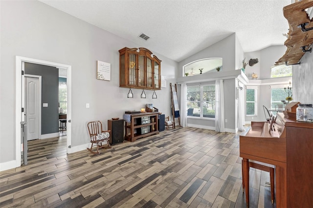 living area with baseboards, visible vents, high vaulted ceiling, wood tiled floor, and a textured ceiling