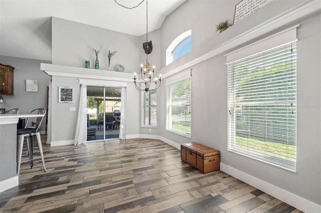 dining room featuring a notable chandelier, a towering ceiling, baseboards, and wood finished floors