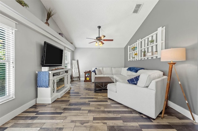 living area featuring visible vents, a ceiling fan, wood finished floors, baseboards, and lofted ceiling