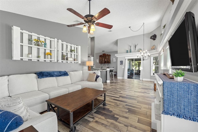 living area with high vaulted ceiling, ceiling fan with notable chandelier, a textured ceiling, wood finished floors, and baseboards