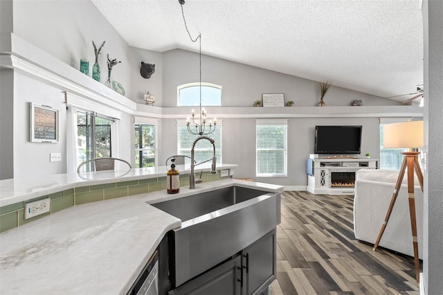 kitchen with a sink, a chandelier, lofted ceiling, and wood finished floors