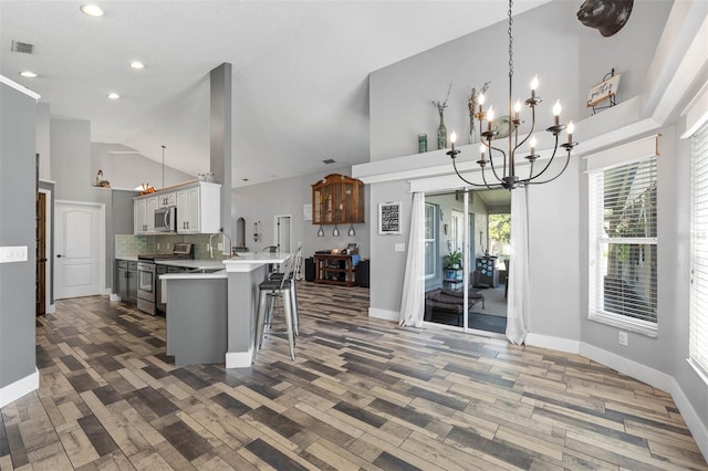 kitchen with visible vents, a kitchen bar, light countertops, a notable chandelier, and stainless steel appliances