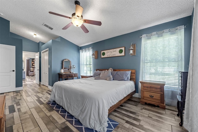 bedroom featuring visible vents, ceiling fan, vaulted ceiling, wood finished floors, and a closet