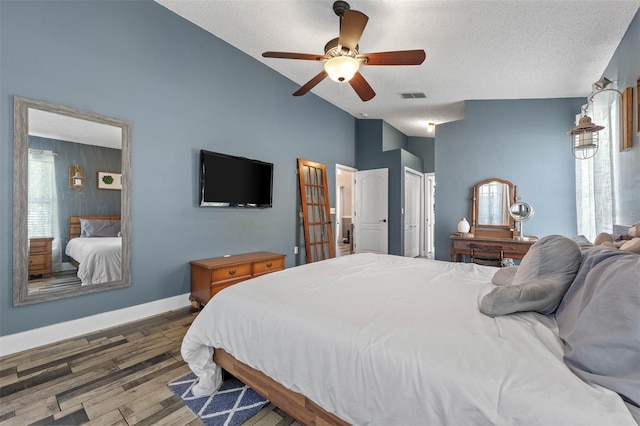 bedroom featuring visible vents, baseboards, lofted ceiling, wood finished floors, and a textured ceiling