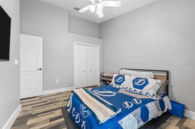 bedroom with ceiling fan, wood finished floors, a closet, and baseboards