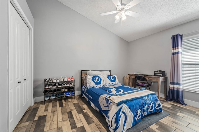 bedroom with wood finished floors, ceiling fan, vaulted ceiling, a closet, and a textured ceiling