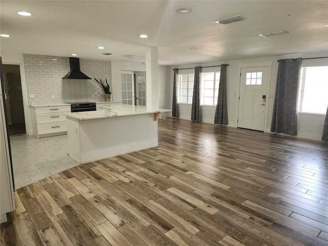 kitchen with visible vents, wood finished floors, black range with electric cooktop, open floor plan, and wall chimney exhaust hood