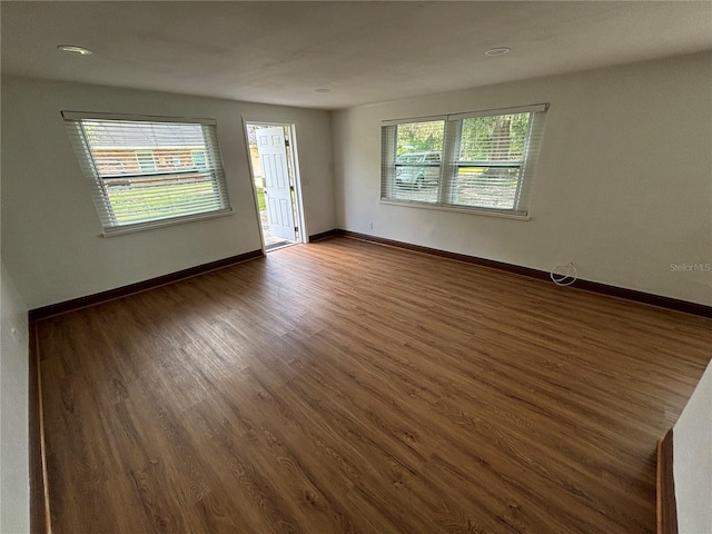 unfurnished room with baseboards and dark wood-style flooring