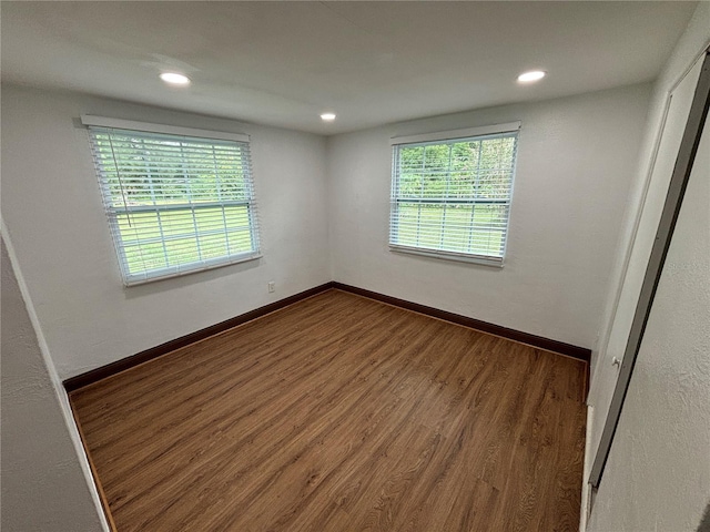 empty room with recessed lighting, wood finished floors, and baseboards