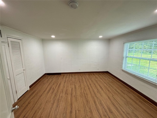 spare room featuring recessed lighting, wood finished floors, baseboards, and ornamental molding