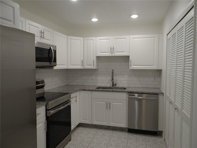 kitchen with white cabinets, appliances with stainless steel finishes, stone countertops, and a sink