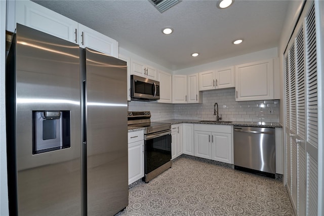 kitchen with visible vents, a sink, dark stone counters, appliances with stainless steel finishes, and white cabinets