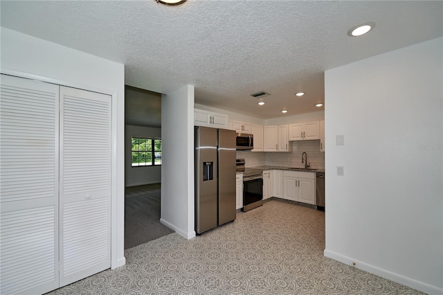 kitchen featuring visible vents, a sink, stainless steel appliances, white cabinetry, and tasteful backsplash