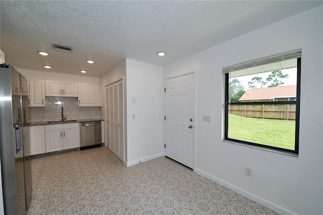 kitchen featuring visible vents, a sink, tasteful backsplash, stainless steel appliances, and white cabinets