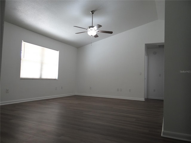 spare room featuring a ceiling fan, vaulted ceiling, baseboards, and dark wood-type flooring