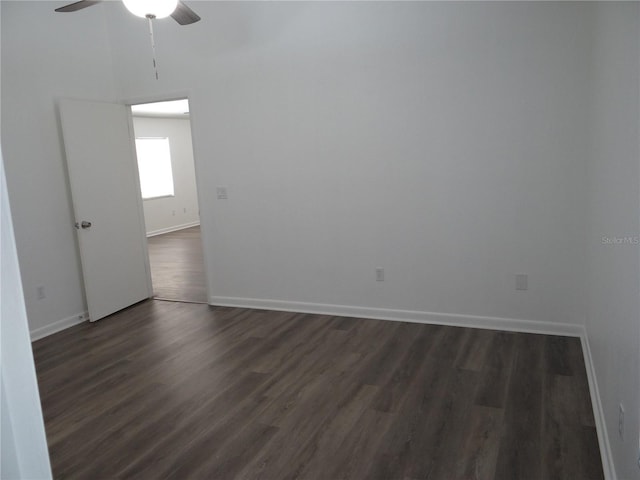 unfurnished room with baseboards, ceiling fan, and dark wood-style flooring