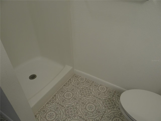 full bathroom featuring tile patterned flooring, a stall shower, toilet, and baseboards