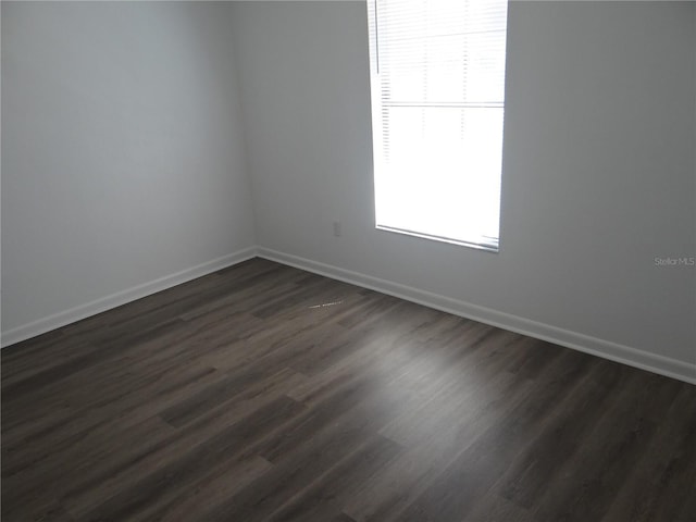 empty room featuring baseboards and dark wood-style flooring