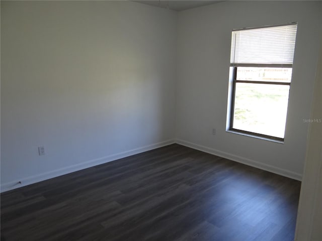 unfurnished room featuring baseboards and dark wood-type flooring