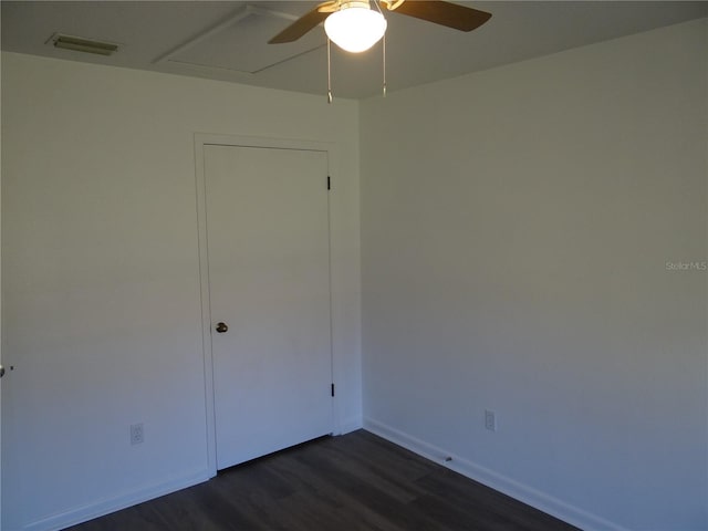 spare room featuring ceiling fan, visible vents, baseboards, and dark wood finished floors