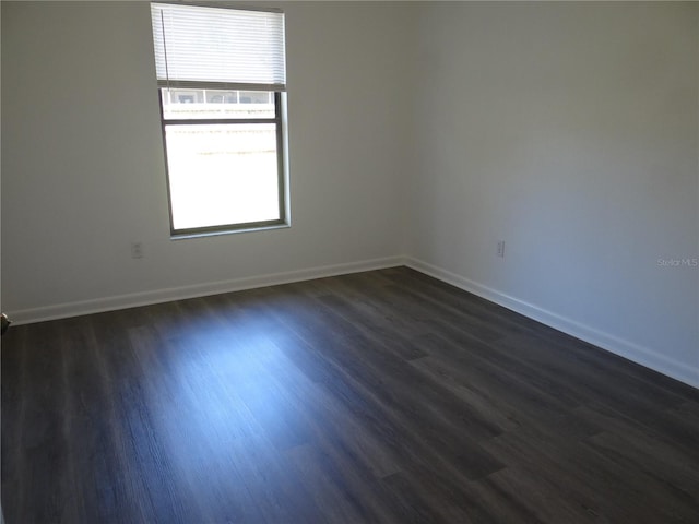 spare room with dark wood finished floors and baseboards