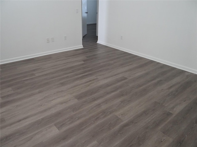 unfurnished room featuring baseboards and dark wood-style flooring