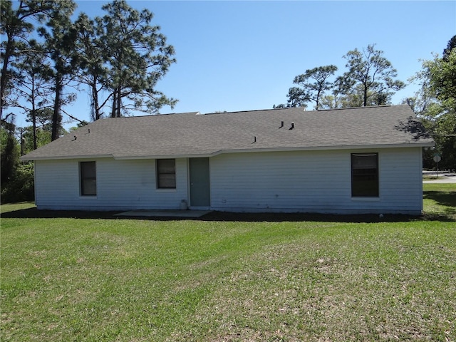 back of house with a lawn and roof with shingles