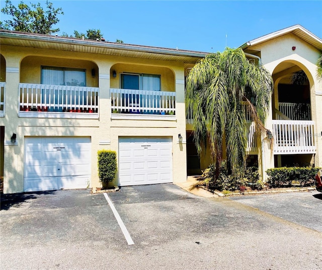 townhome / multi-family property featuring aphalt driveway, stucco siding, and an attached garage