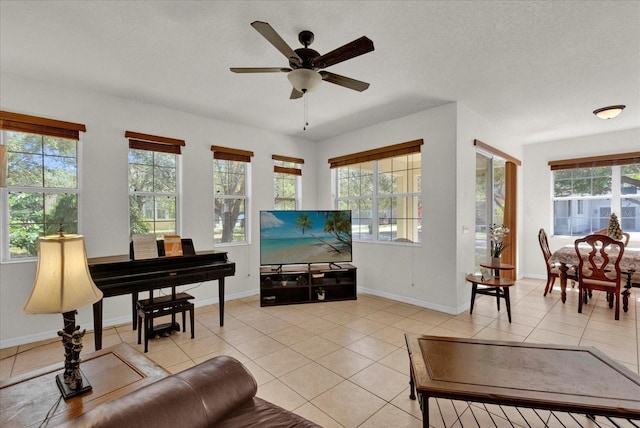 living room featuring a ceiling fan, light tile patterned floors, a healthy amount of sunlight, and baseboards