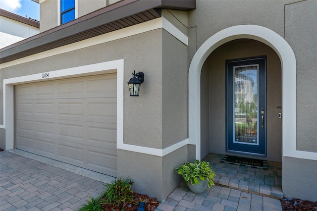 12654 Oak Hill Way, Parrish, FL 34219 - view of exterior entry with stucco siding, a garage, and decorative driveway