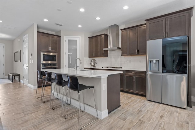 12654 Oak Hill Way, Parrish, FL 34219 - kitchen featuring appliances with stainless steel finishes, wall chimney exhaust hood, a sink, dark brown cabinetry, and a kitchen bar