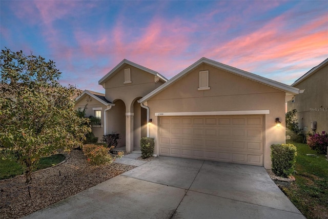 view of front facade with stucco siding, concrete driveway, and an attached garage