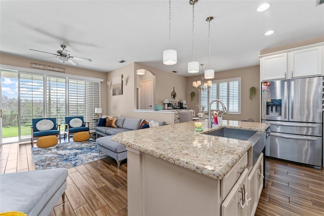 kitchen featuring wood finish floors, a sink, white cabinets, stainless steel refrigerator with ice dispenser, and ceiling fan with notable chandelier