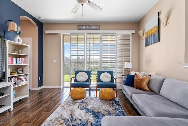 living area with arched walkways, baseboards, a ceiling fan, and wood finished floors