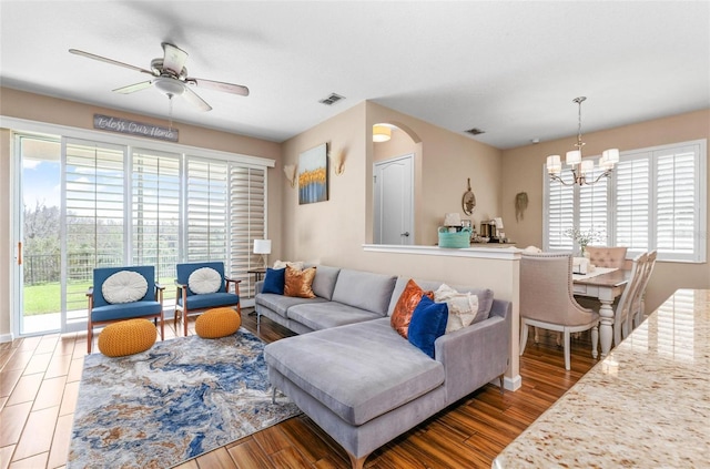 living room featuring arched walkways, visible vents, ceiling fan with notable chandelier, and wood finished floors