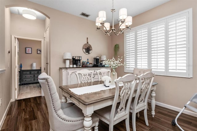 dining space with arched walkways, visible vents, an inviting chandelier, and wood finished floors