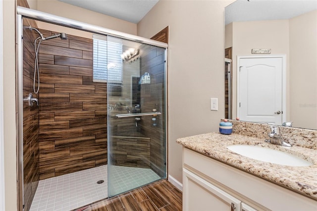 bathroom featuring a shower stall, vanity, and wood tiled floor