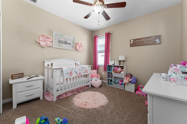 bedroom featuring visible vents, a crib, carpet floors, baseboards, and ceiling fan