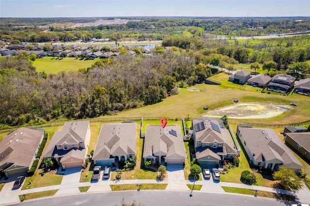 drone / aerial view featuring a view of trees, a residential view, and a water view